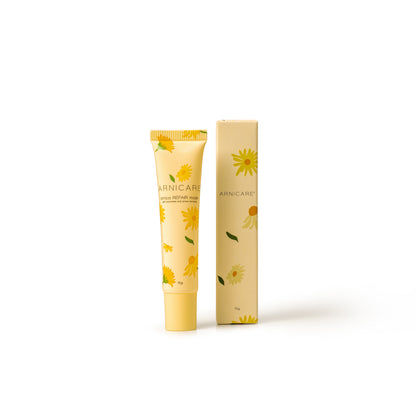 A tube and matching box of Arnicare Repair Mask, decorated with yellow daisy illustrations on a pale yellow background, set against a plain white studio background.