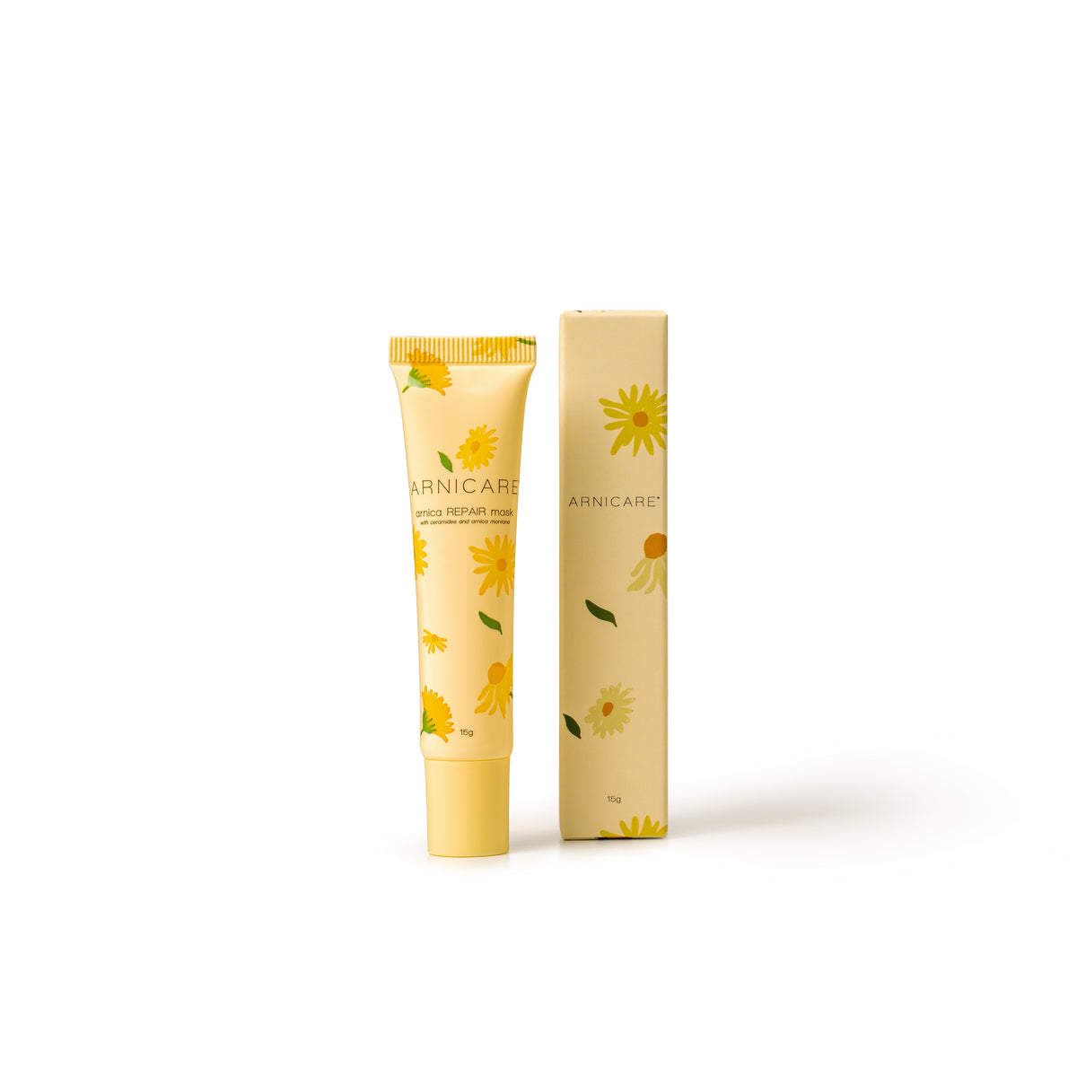 A tube and matching box of Arnicare Repair Mask, decorated with yellow daisy illustrations on a pale yellow background, set against a plain white studio background.