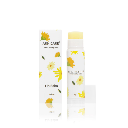 Arnicare Arnica Healing lip balm stick with its matching white and yellow floral box, shown on a clean white background with a soft reflection.