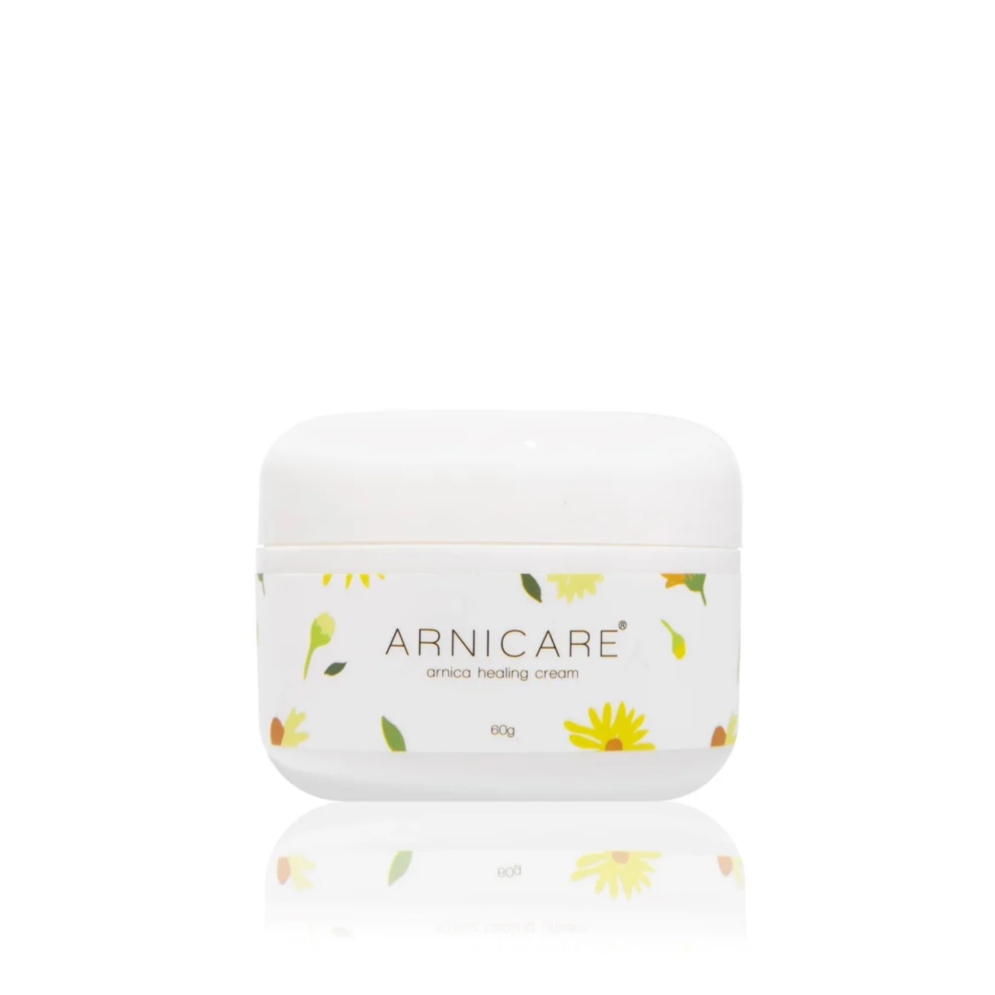 A white plastic jar of ARNICARE arnica healing cream with a white lid, decorated with small yellow flowers and green leaves, set against a solid white background with a soft reflection below.