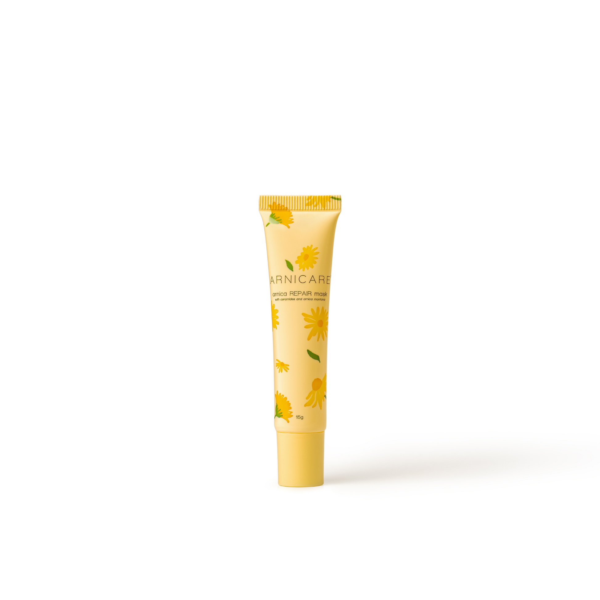 A yellow tube of Arnicare Repair Mask with a daisy floral pattern, standing upright on a white background with a soft shadow.