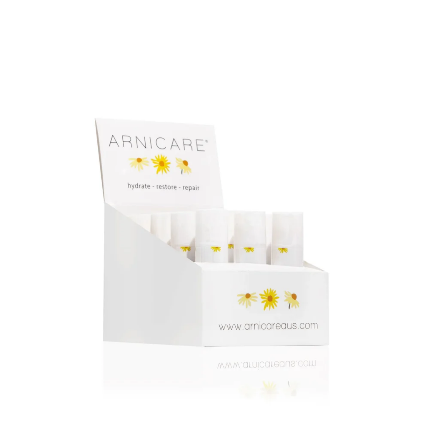 A white ARNICARE product display box containing several small white Arnicare Healing Balms with yellow daisy illustrations, photographed on a clean white background.